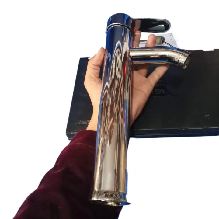 A person holds a tall chrome bathroom faucet and basin mixer, showcasing its polished finish and modern design.