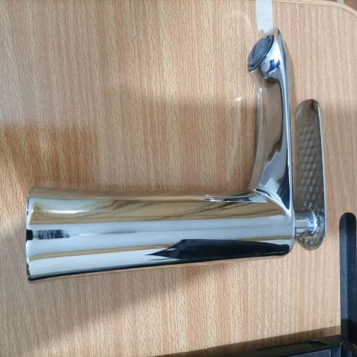 A side view of the basin mixer on a wooden surface, showing its full length and polished stainless steel faucet finish.